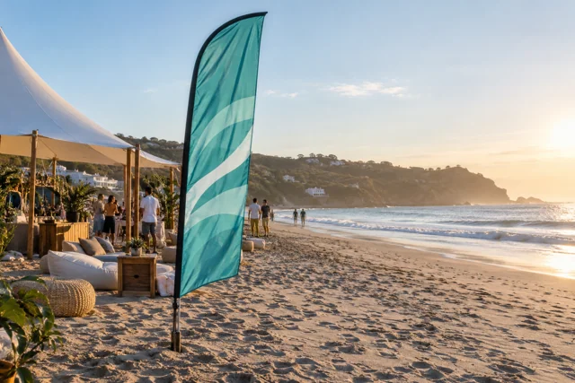 Sea-green advertising flag beside a quiet beachfront event area
